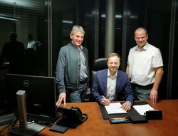 Stefan Haberl unterschreibt am Wahlabend ein Dokument am Schreibtisch des Bürgermeisters. Franz Hofstetter und Verwaltungsleiter Martin Bauer stehen hinter ihm. 