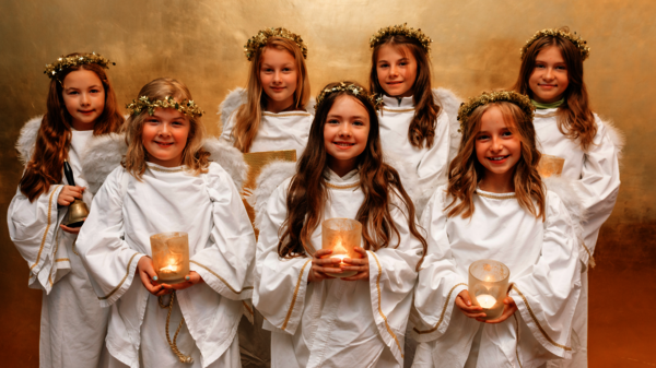 Sieben Kinder in Engelkostümen vor goldener Wand